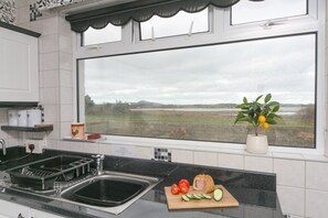 A kitchen with a large window, a sink, a cutting board with vegetables, and a plant. - Peaceful property with stunning views - Pass the Keys (Four Mile Bridge)