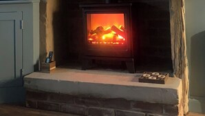 Un camino con un fuoco acceso, un quadro incorniciato sopra e una piccola scatola con candele sulla mensola.