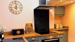 Una cucina compatta con forno integrato, microonde e macchina del caffè sul piano di lavoro.