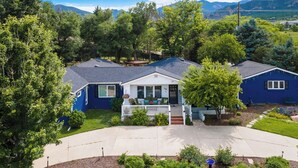 A two-story house with a front porch, surrounded by lush greenery and a clear sky. - Broadmoor Spacious 4-bd 3 bth house with Mountain View’s 3 mins to The Broadmoor (Colorado Springs)