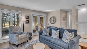 Een woonkamer met een bank, fauteuil en een rond salontafel.