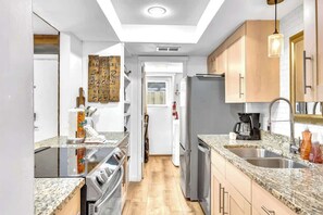 Una cocina moderna con encimeras de granito, electrodomésticos de acero inoxidable y armarios de madera.
