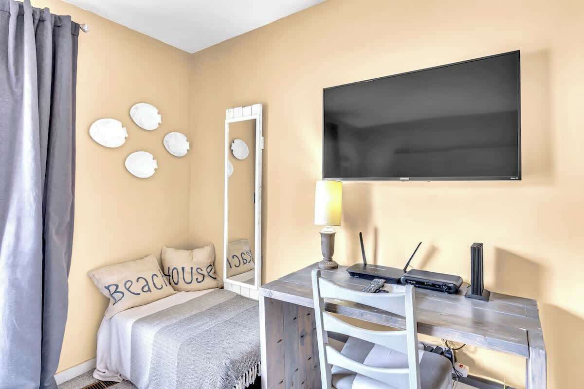 Un dormitorio con una cama, un escritorio con una silla, un televisor y un espejo.