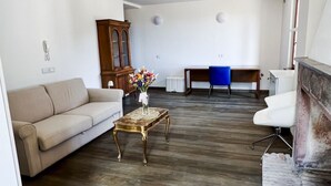 Ein Wohnzimmer mit einer Couch, einem Holzschrank, einem Schreibtisch und einem Sessel.