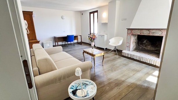 Ein Wohnzimmer mit einer Couch, einem kleinen Tisch mit einer Lampe, einem Kamin und einem Essbereich mit einem Stuhl und Tisch.