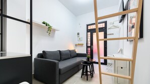 Un salon moderne avec un canapé noir, une petite table ronde et une échelle en bois.