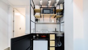 Une cuisine compacte équipée d’un four à micro-ondes, d’un évier et de placards de rangement.