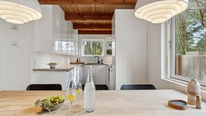 A modern kitchen with white cabinets, a wooden ceiling, and pendant lights. - "Bedrija" - 200m from the sea by Interhome (Nexø)