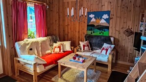 A cozy wooden cabin interior with a sofa, two chairs, a coffee table, and a painting on the wall. - Gördalen by Interhome (Särna)