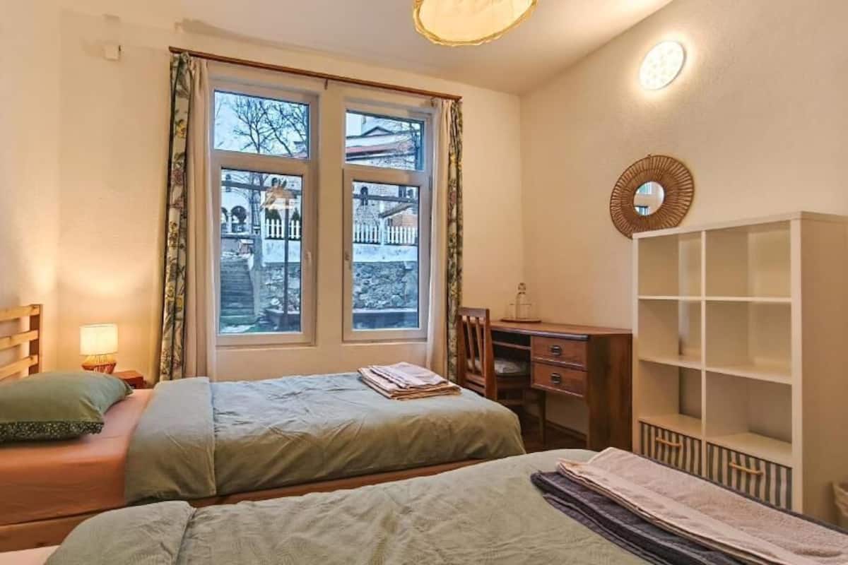 Una camera da letto con due letti, una finestra vista, un comodino con lampada e un armadio.
