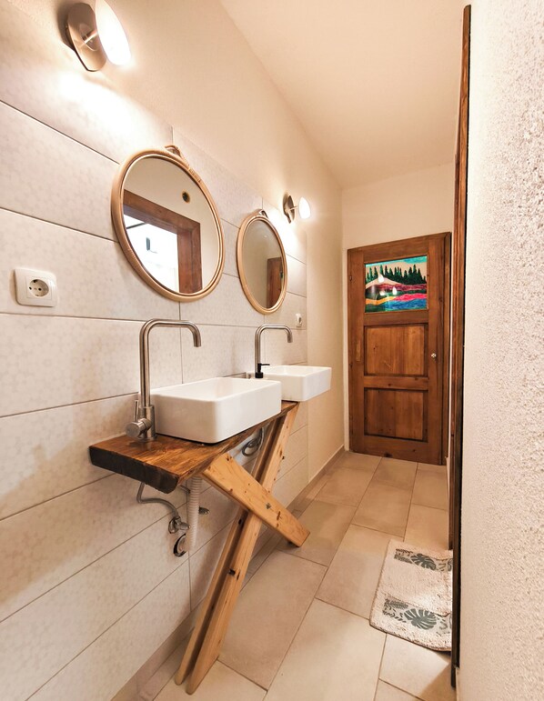 A bathroom with two sinks, a wooden shelf, a mirror, and a door with a colorful painting. - PORTALA Urban Lodge (Rila)