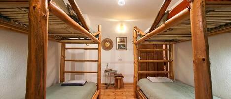 Habitación con literas de madera, una mesita pequeña y un reloj de pared.