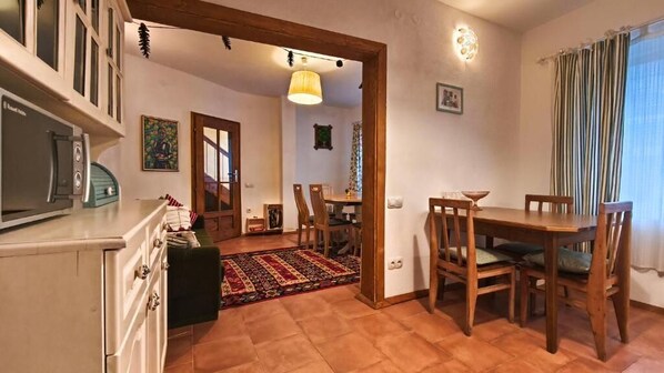 A dining area with wooden furniture, a kitchen with white cabinets, and a patterned rug. - PORTALA Urban Lodge (Rila)