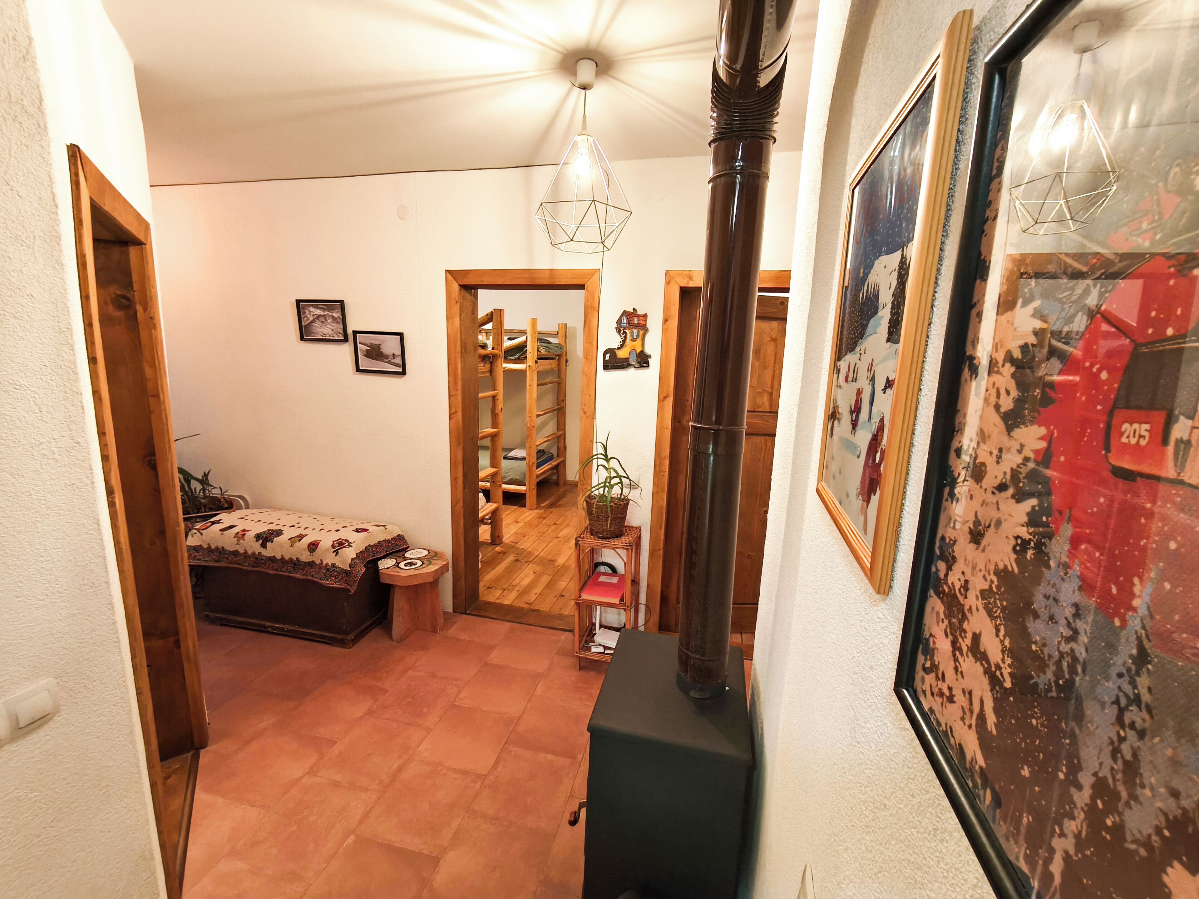 A narrow hallway with a bed, a wooden ladder, a radiator, and a framed picture on the wall.