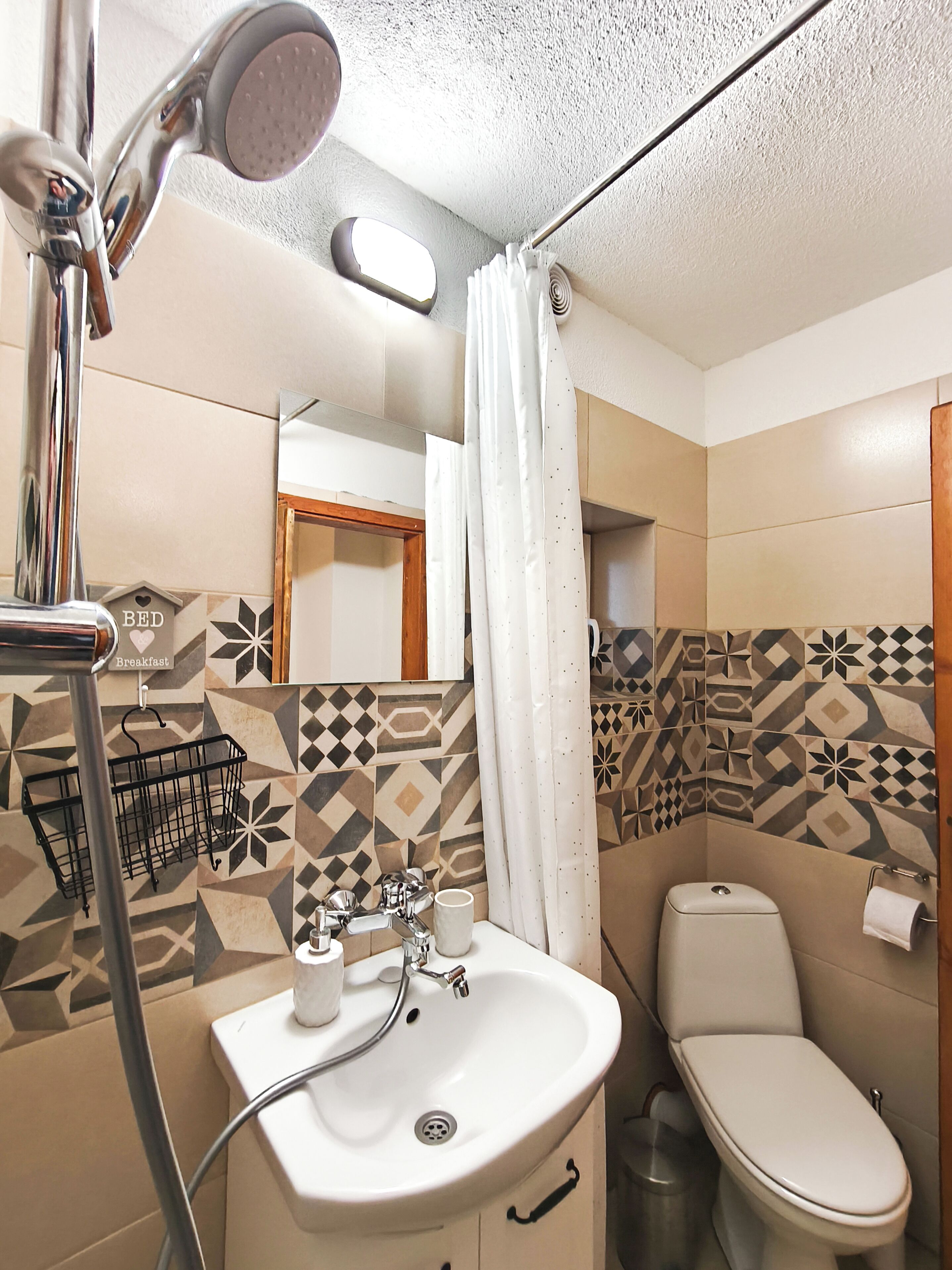 Une salle de bain équipée d’un lavabo, de toilettes, d’une douche et de carreaux décorés.
