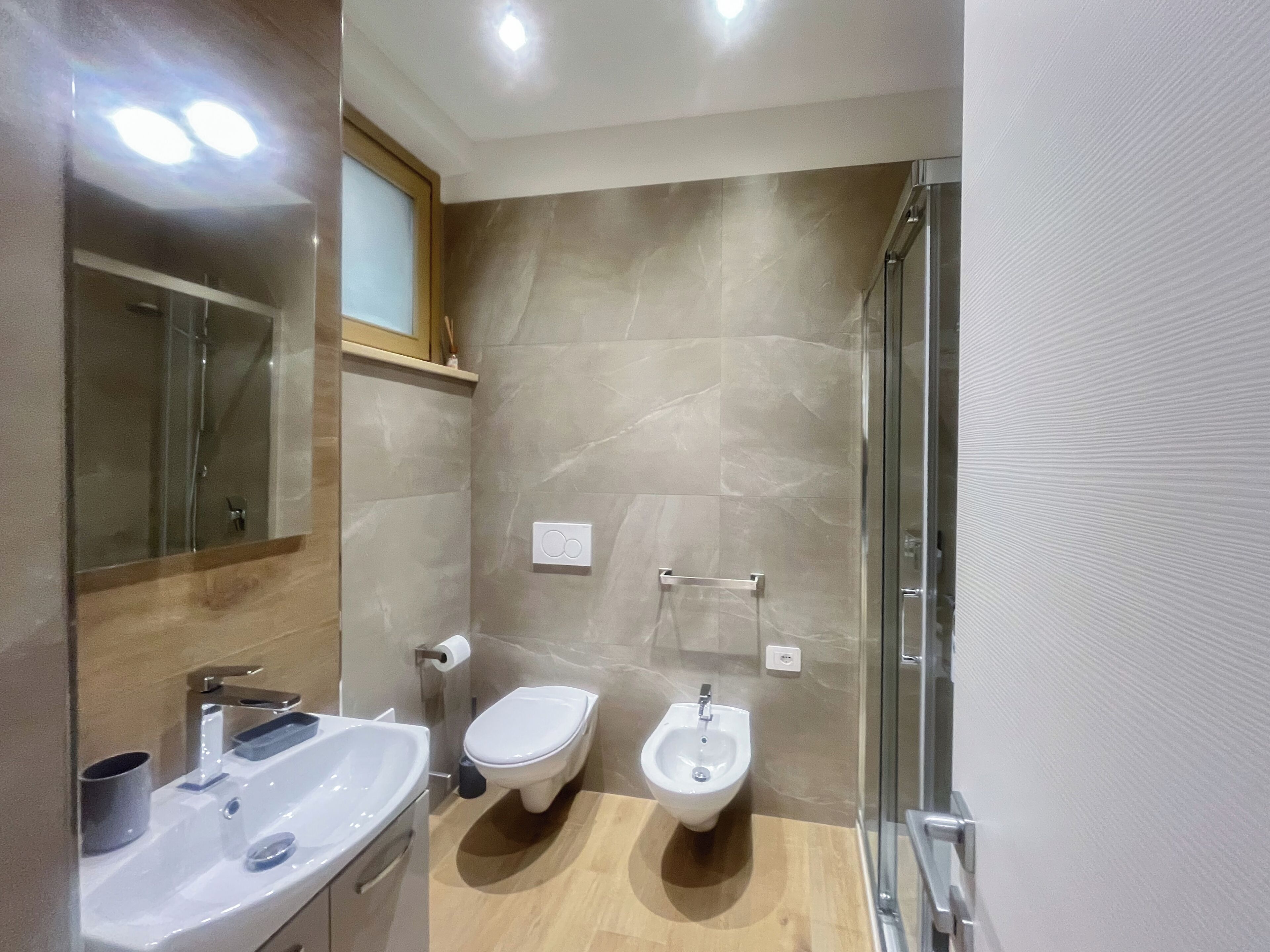 Une salle de bain moderne équipée d’un lavabo, de toilettes, d’un bidet et d’une douche à parois de verre.