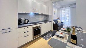 A modern kitchen with white cabinets, a built-in oven, and a dining area with a table set for two.