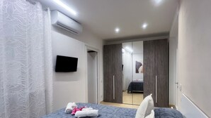A bedroom with a bed, a flat-screen TV, a wardrobe, and a mirror.