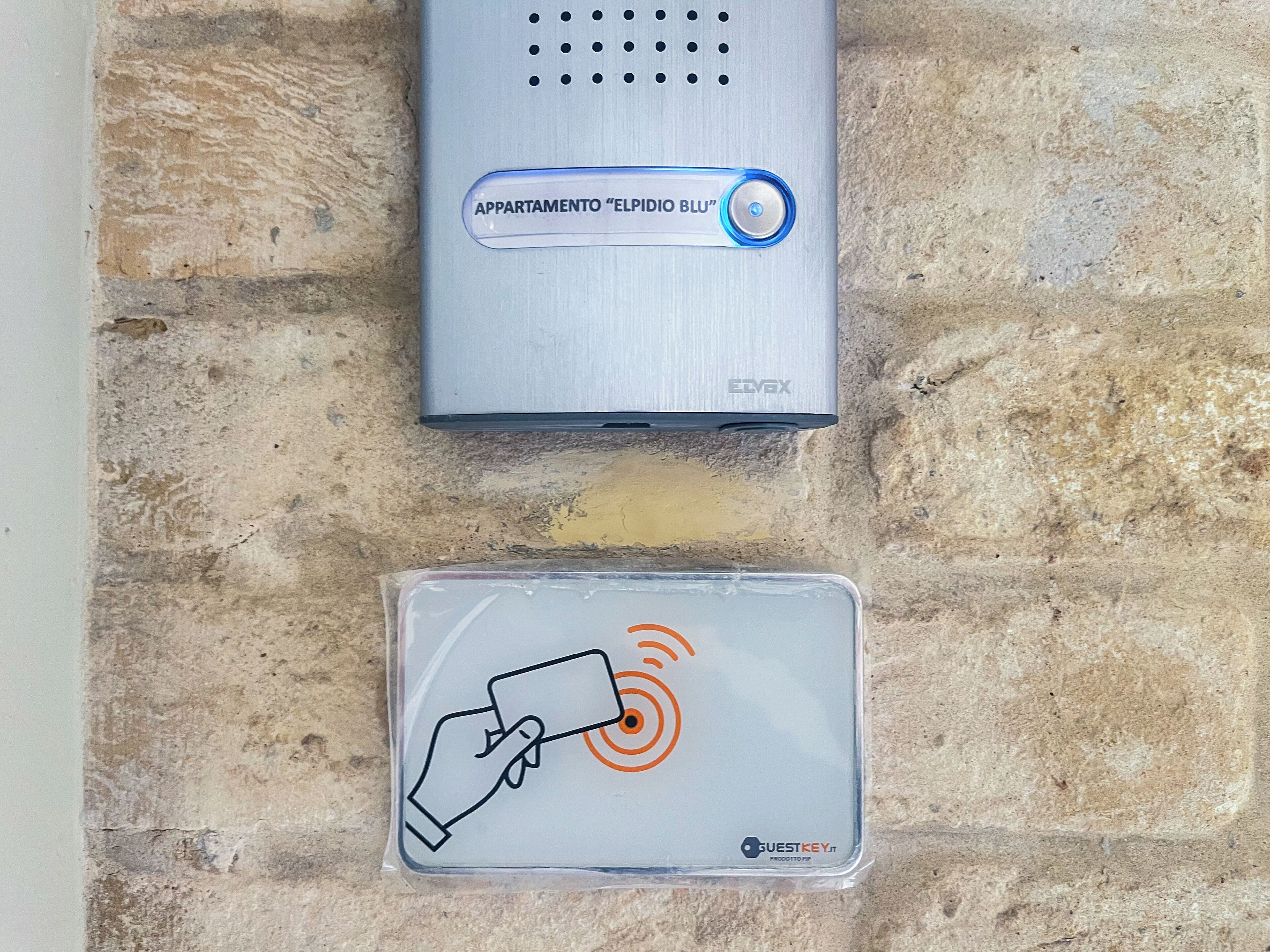 A digital key card and a wall-mounted device, likely a security or access system, on a textured stone wall.