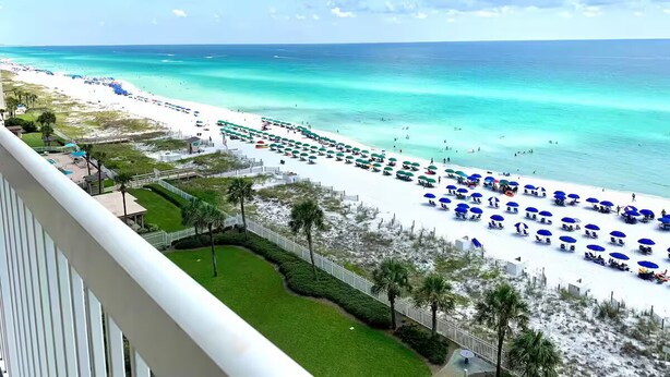 A beach view from a balcony with a white railing, a sandy beach, and a clear blue sky. - Luxury ON BEACH Condo with great pool too (Destin)