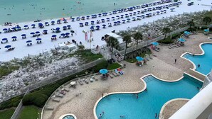 A beach resort with a large pool area, beach umbrellas, and a view of the ocean. - Luxury ON BEACH Condo with great pool too (Destin)
