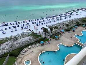 Ein Strandresort mit großzügiger Poolanlage, Strandsonnenschirmen und Blick aufs Meer.