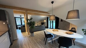 Une cuisine moderne dotée d’un îlot central, de revêtements de sol en bois et d’un coin repas avec une table ronde et des chaises.