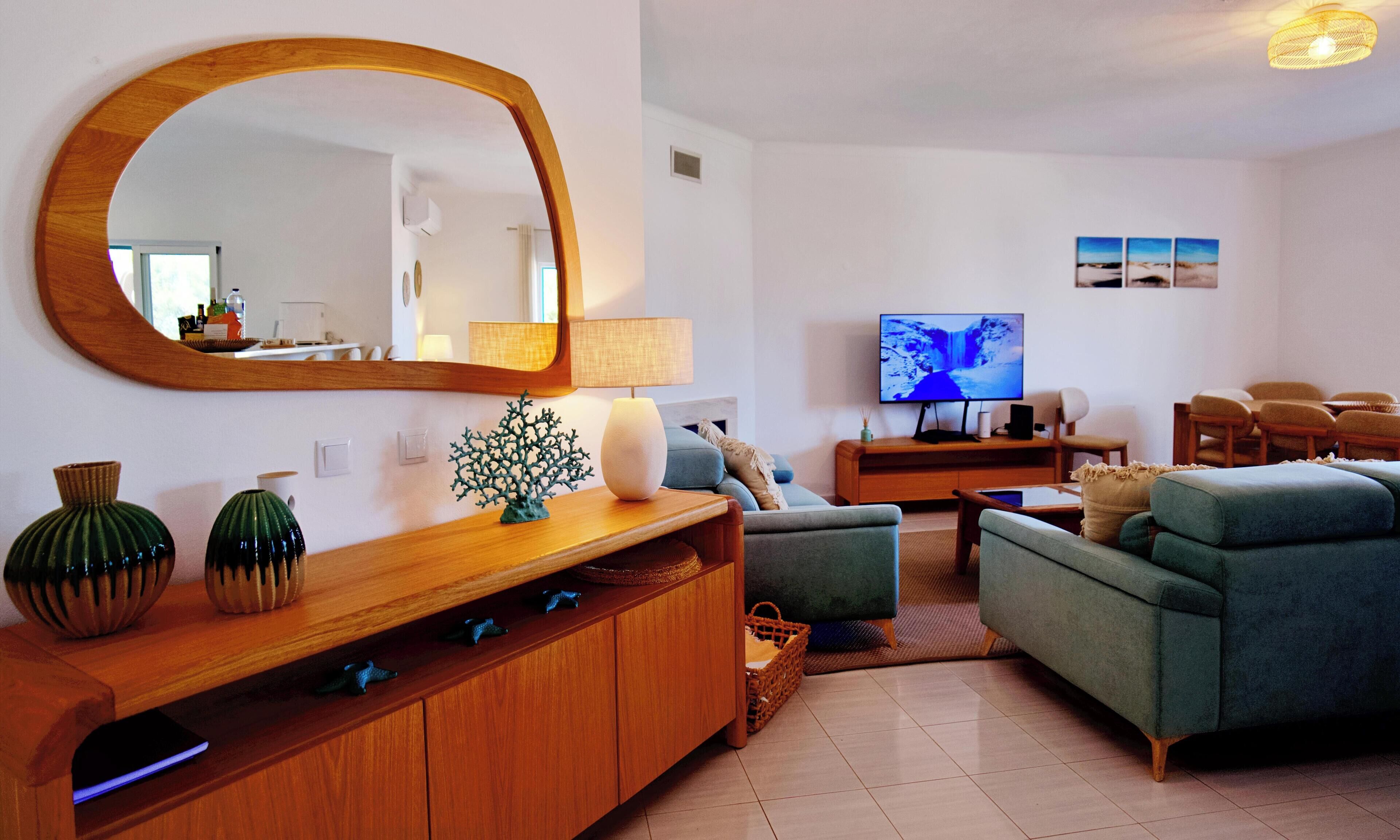 Een woonkamer met een grote spiegel, een televisie en een bank.