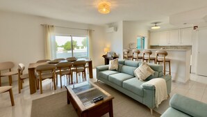 Ein modernes Wohnzimmer mit Sofa, Couchtisch und Essbereich.