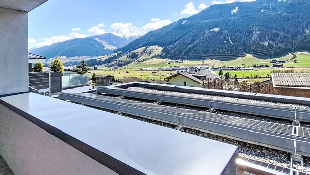 Un balcon avec vue sur une gare, des montagnes et un village.