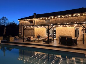 A stone building with outdoor seating and a pool.