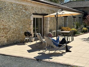 A patio with a stone wall, a grill, and outdoor furniture. - Le Jardin d'Elusa - Gîte Le Chai (**** 4 stars) (Eauze)