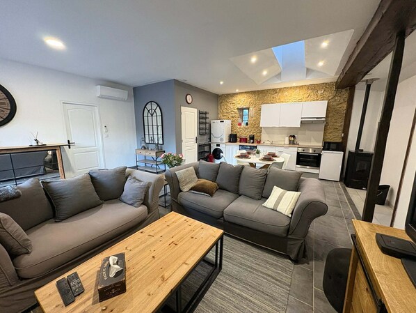A modern living room with a sofa set, a coffee table, and a kitchen area with cabinets and a stone accent wall.