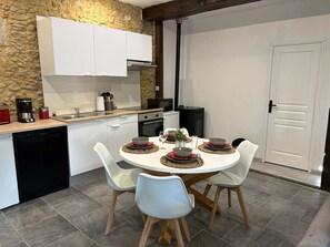 A modern kitchen with white cabinets, a stone wall, and a dining area with a round table and four chairs.