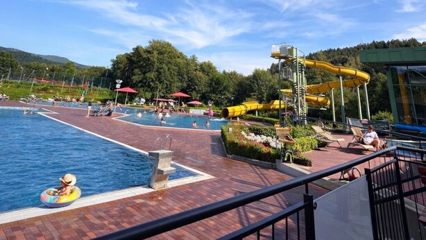 A swimming pool area with a water slide, lounge chairs, and a view of the surrounding landscape. - Bavaria Mountain Designer Chalet vacation apartment at the Arber SKI dog pool sauna spa (Lohberg)