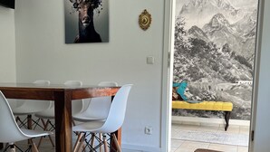 A dining area with a wooden table and chairs, a large painting of a deer, and a view of mountains through a glass door. - Bavaria Mountain Designer Chalet vacation apartment at the Arber SKI dog pool sauna spa (Lohberg)