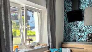 A cozy living room with a brown sofa, teal cushions, a coffee table, and a window with curtains. - Bavaria Mountain Designer Chalet vacation apartment at the Arber SKI dog pool sauna spa (Lohberg)