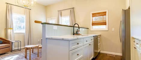 A modern kitchen with white cabinetry, a built-in island, and a stainless steel refrigerator.