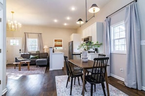 A modern kitchen with white cabinets, a dining table with chairs, and a chandelier. - Pet-Friendly Home with Fenced Yard (Raleigh)