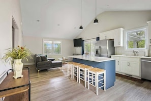 A modern kitchen with a large island, white cabinetry, and a grey sofa in the living area. - Pet Friendly Family Home Steps to Raleigh Greenway (Raleigh)