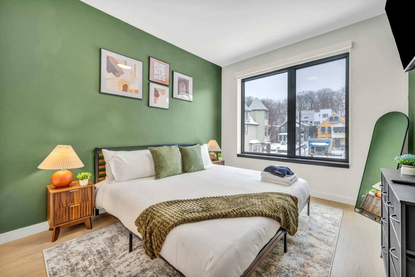 A bedroom with a bed, nightstands, a window, and artwork on the wall.