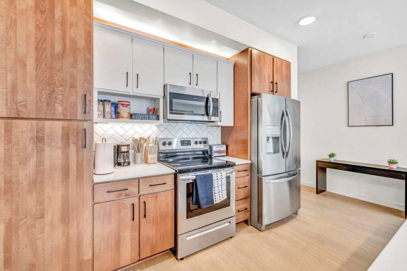 A modern kitchen with wooden cabinets, stainless steel appliances, and a coffee bar.
