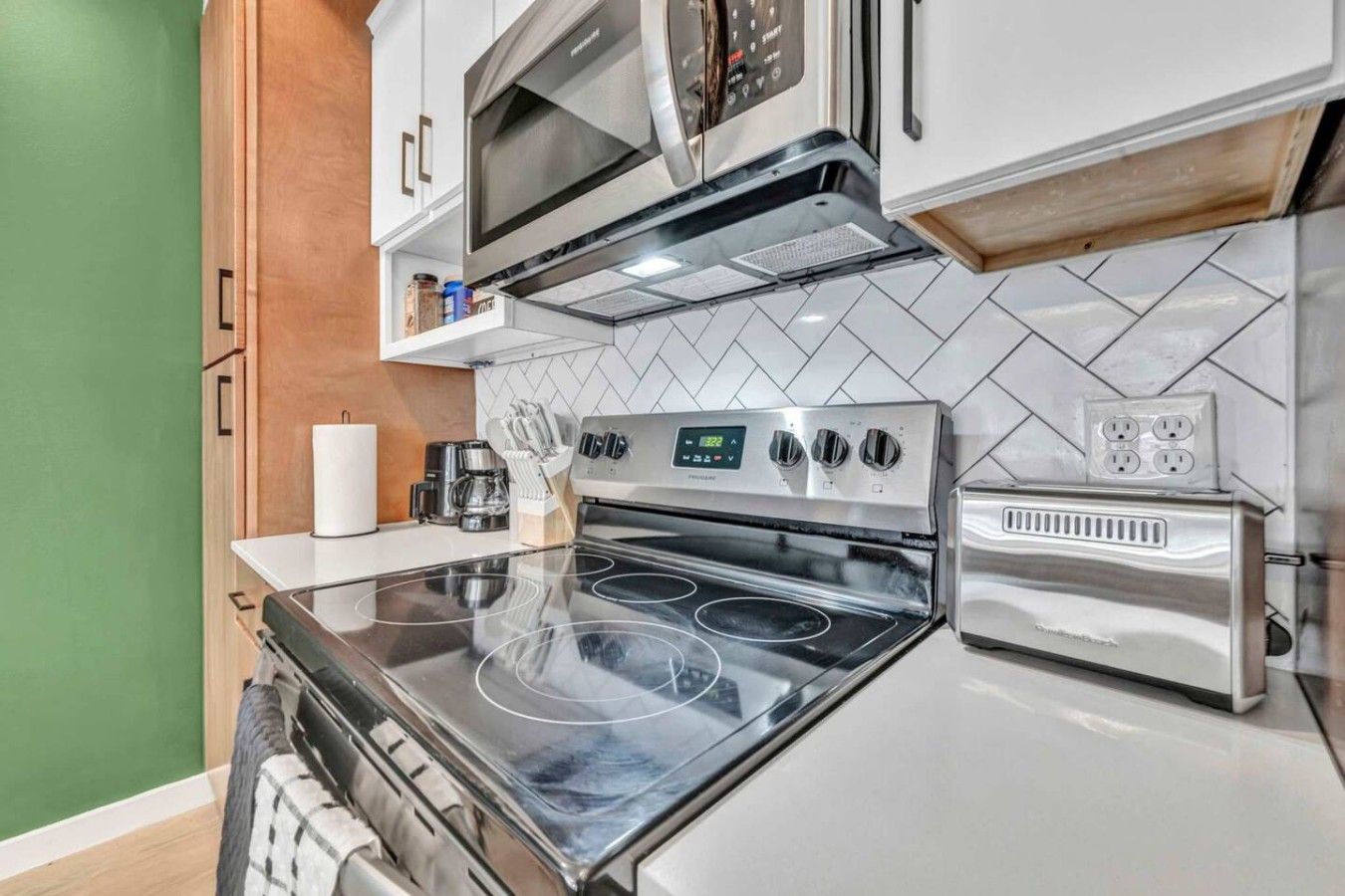 A compact kitchen with a stove, microwave, and toaster.