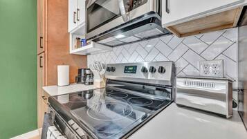 A compact kitchen with a stove, microwave, and toaster.