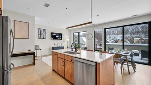 A modern kitchen with a central island, wooden cabinets, stainless steel appliances, and a large window overlooking a snowy landscape. - Cleveland Clinic w KingBed,Balcony,Gym,Parking,WD (Cleveland)