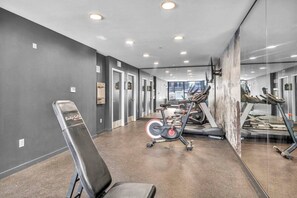 Un gimnasio con equipo de ejercicio, un espejo grande y una puerta que da a otra habitación.