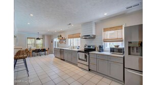 Een moderne keuken met een centraal eiland, inbouwapparatuur en een eethoek met stoelen.