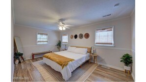 Een slaapkamer met een bed, nachtkastjes, een plafondventilator en een raam met jaloezieën.