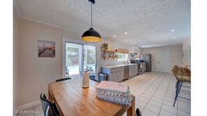 Een ruime keuken met moderne apparatuur, een eethoek met een houten tafel, en een groot raam dat voor natuurlijk licht zorgt.