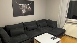 Un soggiorno moderno con un divano componibile, un tavolino da caffè bianco e un'opera d'arte in bianco e nero raffigurante un toro.